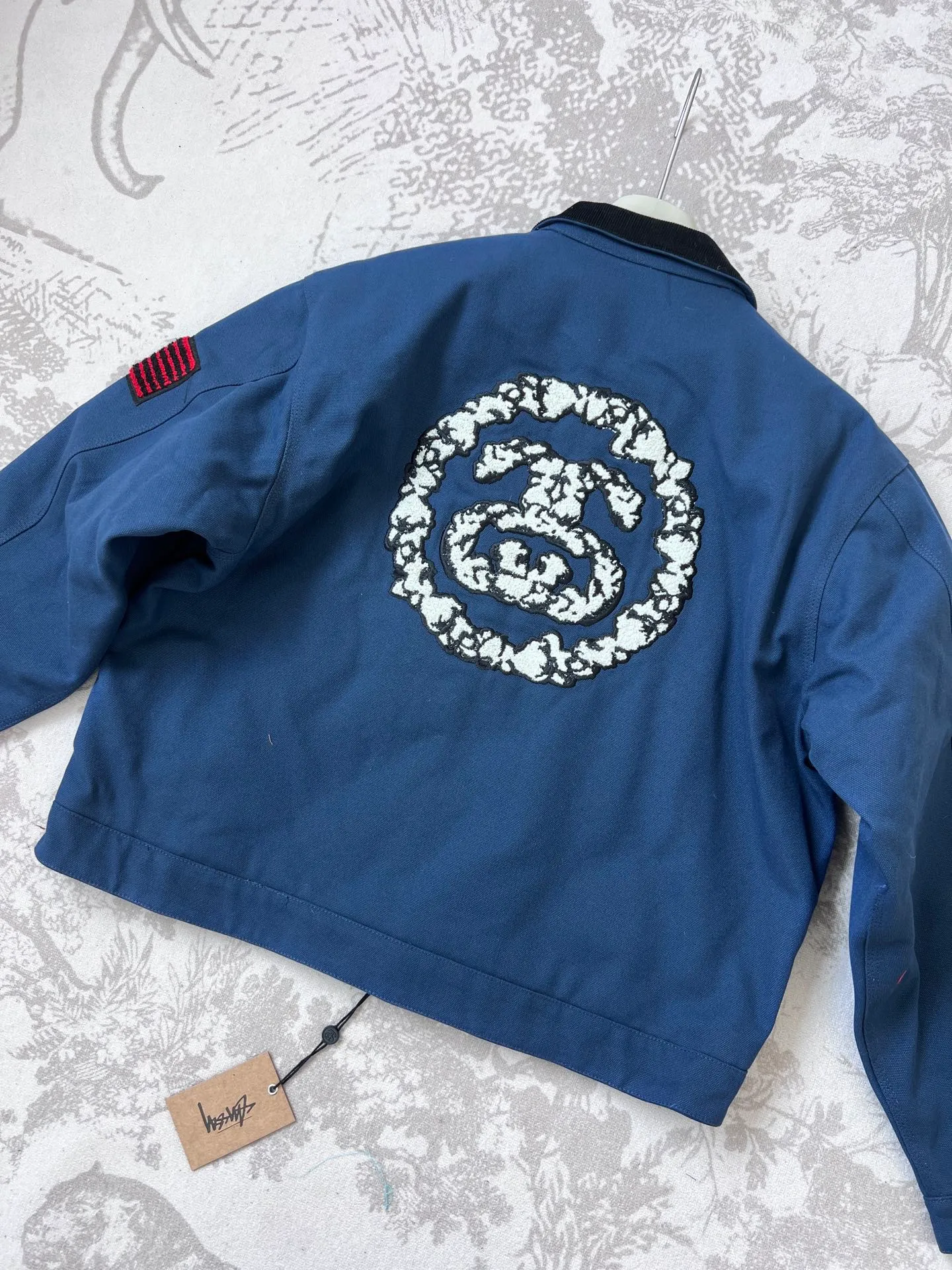 New T66# jacket version 340💰/quilted version 360💰 Stussy x Denim Tears joint model SS25 round chest logo printed zipper opening work jacket, same style for men and women, navy blue Accessories: original dismantling and development, one-to-one customized small labels, collar labels, washing, hang tags, hardware, etc. - Fabric: It is made of the original one-to-one 275g pure cotton fabric, and the high-count double yarn process improves softness and durability. The whole piece is washed, giving it a vintage navy blue distressed texture, echoing the nostalgic tone of the campus theme.   - The collar part is spliced ​​with corduroy or cotton fabrics, which contrasts with the washed cotton of the main body to enhance the visual layering and improve wearing comfort.    - The iconic "Double S + Kapok Ring" combination logo on the back is three-dimensional embroidery. The cotton texture and letter lines stand out in three-dimensionality, enhancing brand recognition.   - A small area of ​​embroidery, card colors and Never Renege slogans are added to the side to echo the cultural theme of the African American community.   - Continuing the short and wide cut of the Detroit work jacket, the cuffs and hem are tightened to give both functionality and practicality.   - The interior adopts quilting technology to provide moderate warmth while maintaining lightness, which is suitable for spring when the temperature difference between morning and evening is large.     - Equipped with YKK metal zipper, it opens and closes smoothly and is durable, and the edge wrapping process improves the overall structural strength.  - African cultural elements: symbols such as the Ace of Spades, the Bid Whist card game scene, and the Jamaican high school area code "718" are integrated into the single product through embroidery, printing and other processes to convey the cultural proposition of Denim Tears.  - Joint logo: Stussy double S logo and Denim Tears kapok ring are combined with embroidery and printing to strengthen the uniqueness of the joint series.  Size: M-2XL M bust 127 length 65.5 sleeve length 61 shoulder width 53.3 [160-165cm 60-70kg] L bust 132 length 66.8 sleeve length 62.2 shoulder width 55.9 [165-170cm 70-85kg] 【170-175cm 80-95kg】 XXL Bust 142.2 Clothes Length 69.3 Sleeve Length 64.8 Shoulder Width 61 【175-180cm 90-105kg】